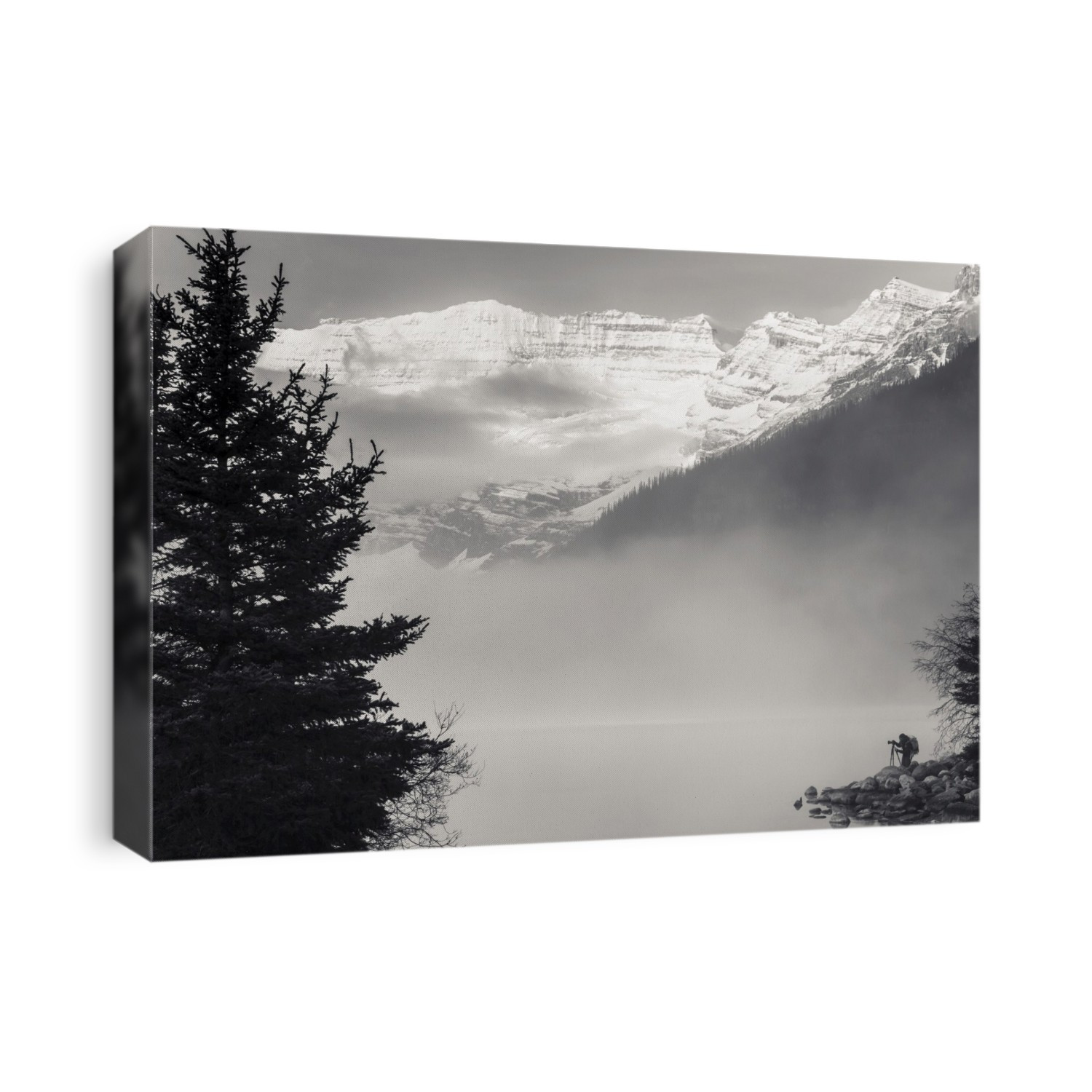Silhouette of a photographer on the shore of Lake Louise with fog rising from the lake at sunrise, Banff National Park; Lake Louise, Alberta, Canada