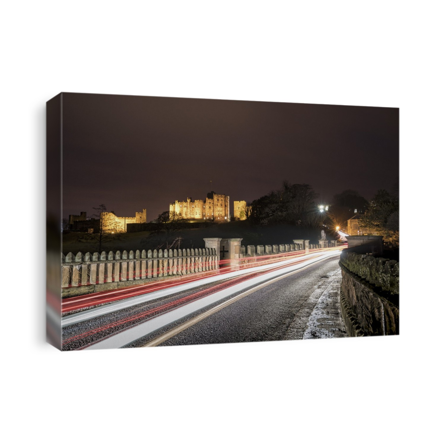 Light Trails On A Road And Illuminated Building In The Background At Nighttime; Alnwick, Northumberland, England
