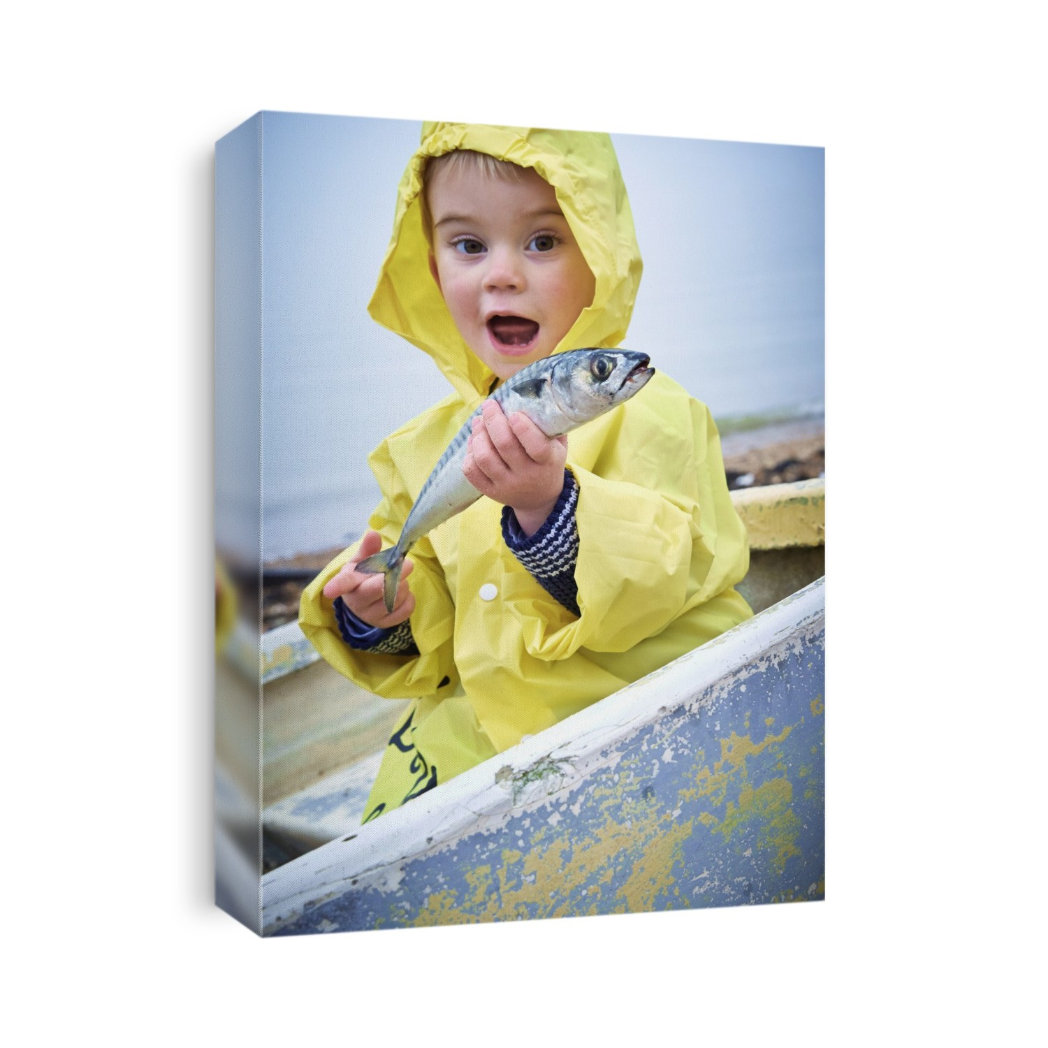 Young boy wearing raincoat holding a mackerel, portrait.