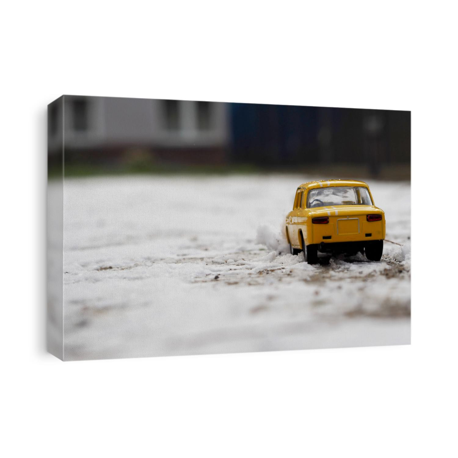 close up a yellow metal small car stands on the snow outside side view . toy on the street