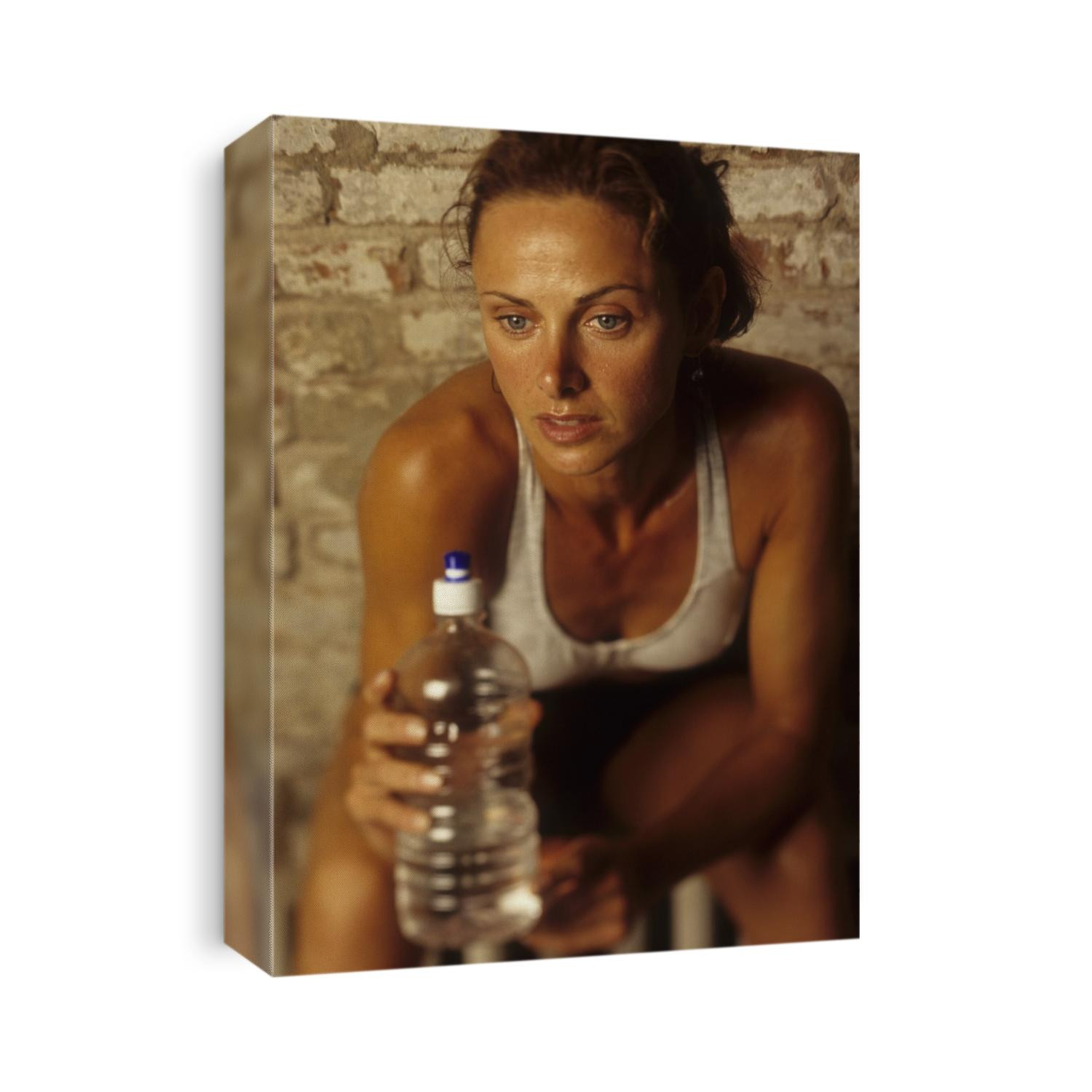 Woman resting and drinking after work out at health club.
