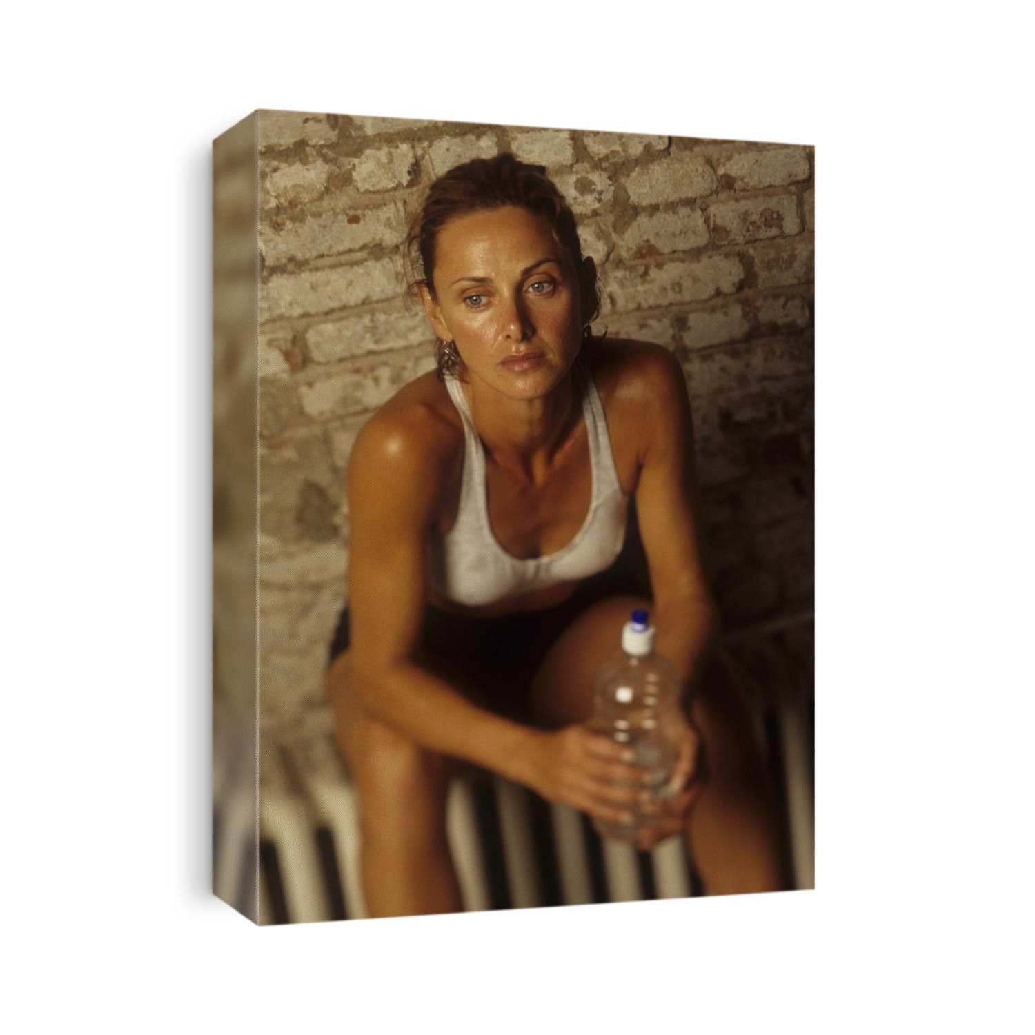 Woman resting and drinking after work out at health club.