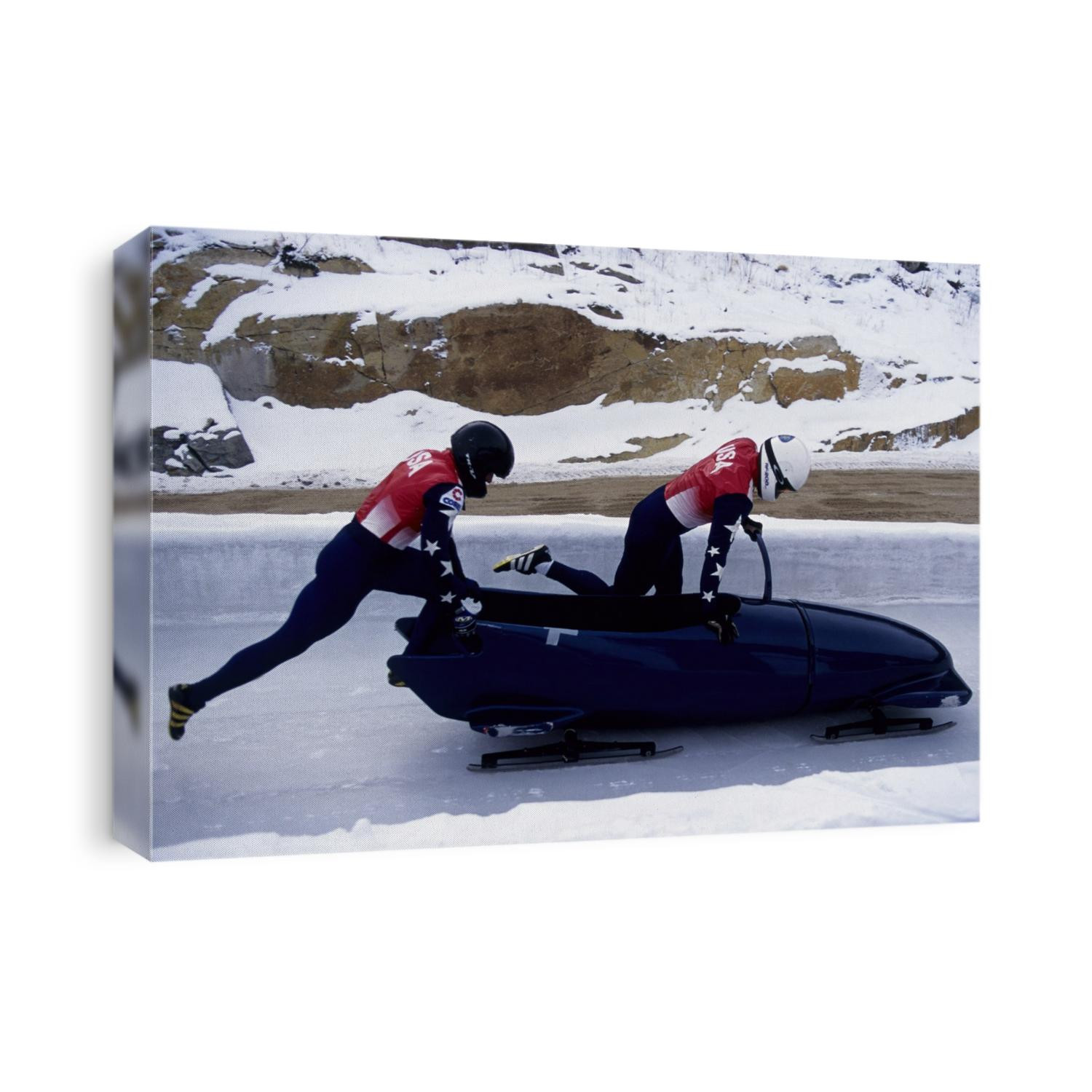 Two man bobsled team pushing off at the start .