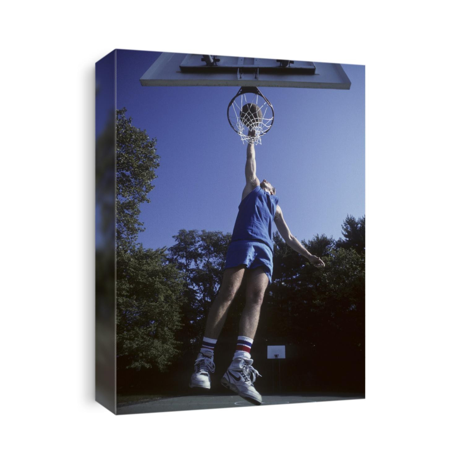 Male basketball player dunking the ball.