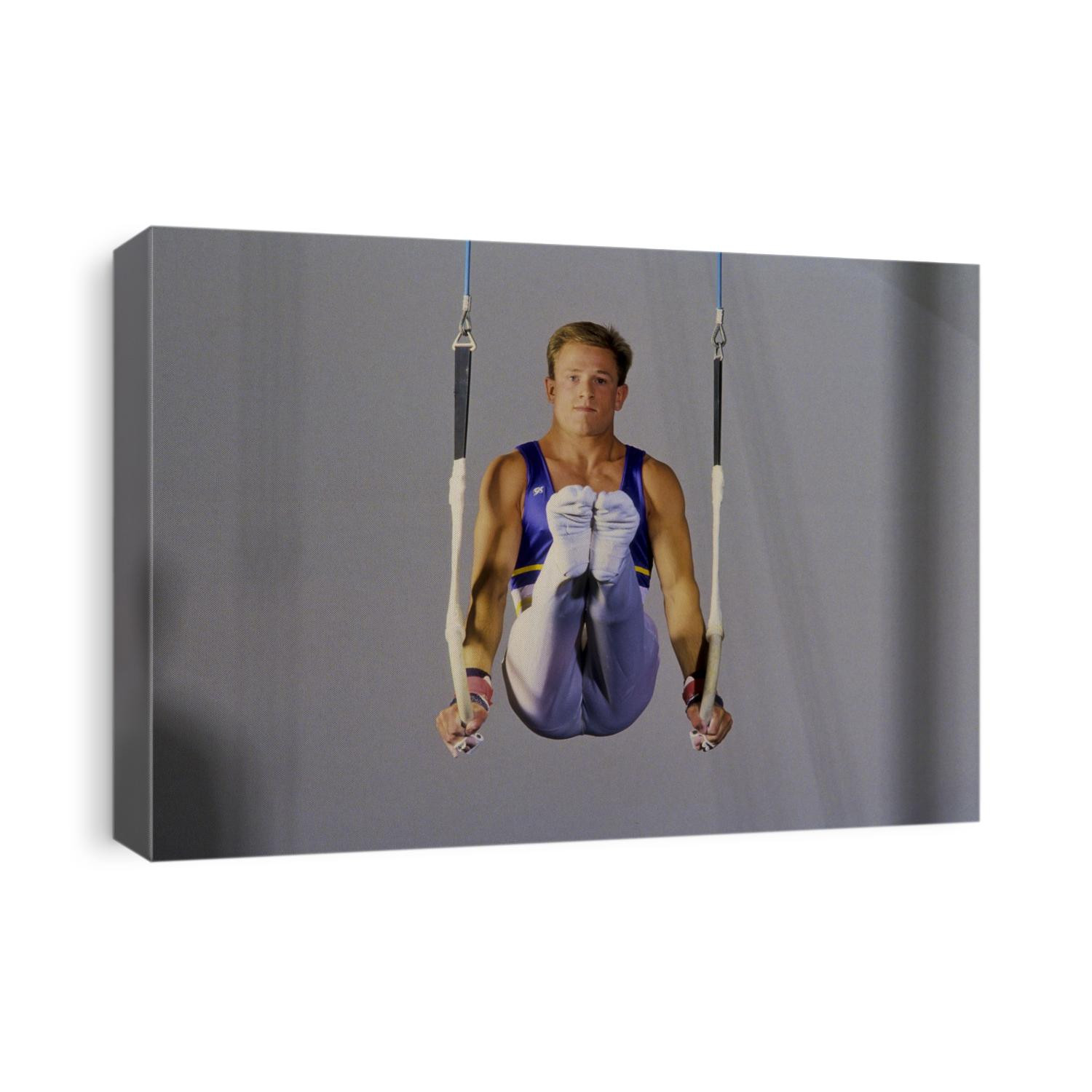 Male gymnast performing on the rings.