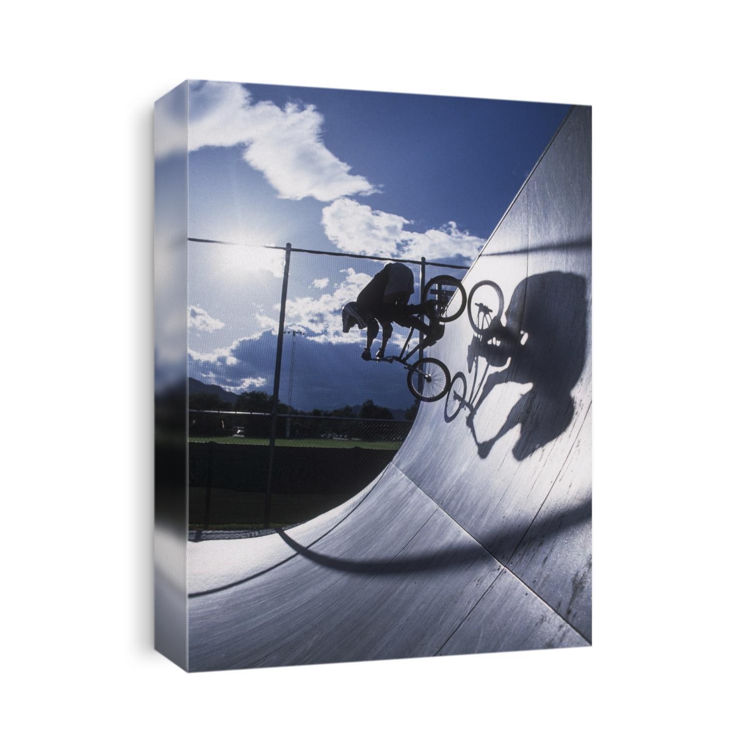 Teenage boy rides over the vert on a BMX bike.