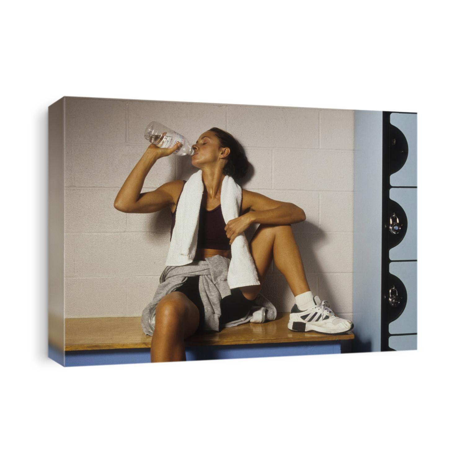 Woman resting and drinking after work out at health club.