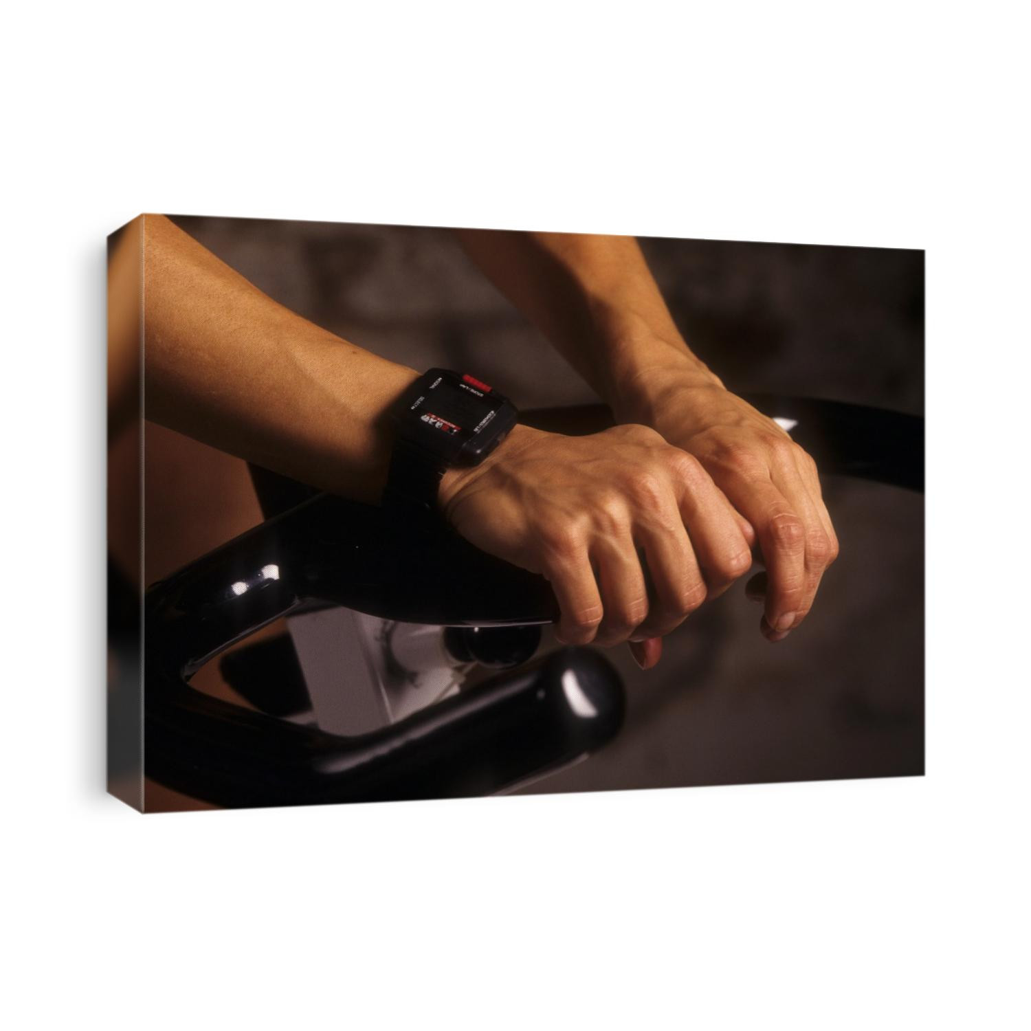 Detail of hands on stationary bike with heart rate monitor watch.