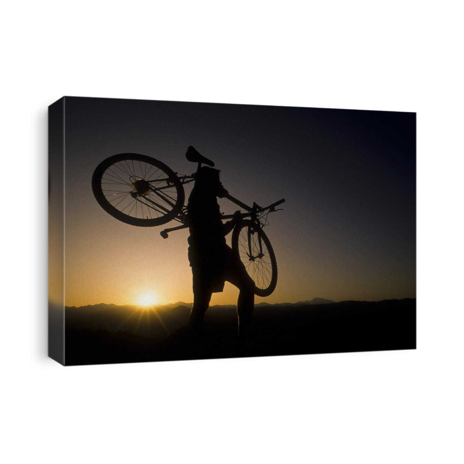 Silhouette of mountain biker at the summit during sunrise.
