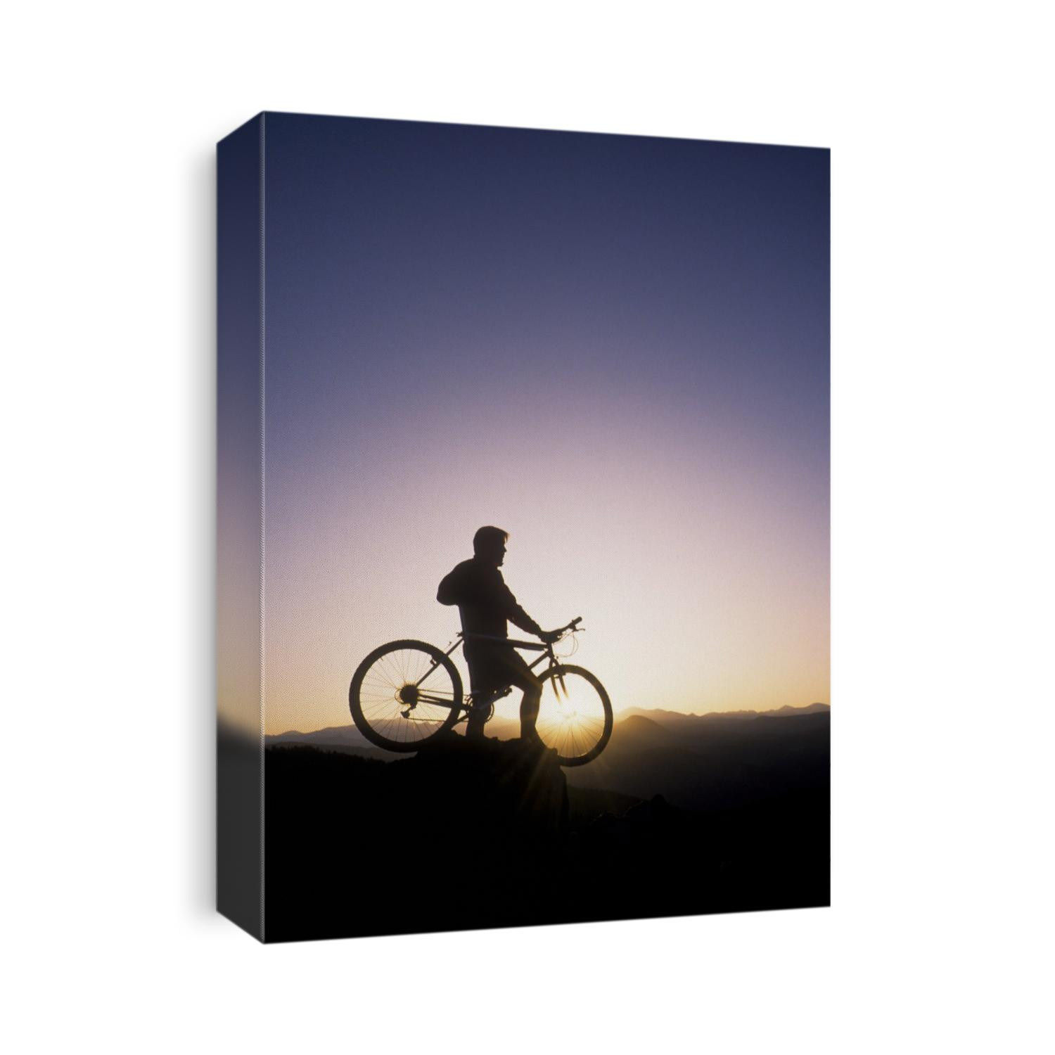 Silhouette of mountain biker at the summit during sunrise.