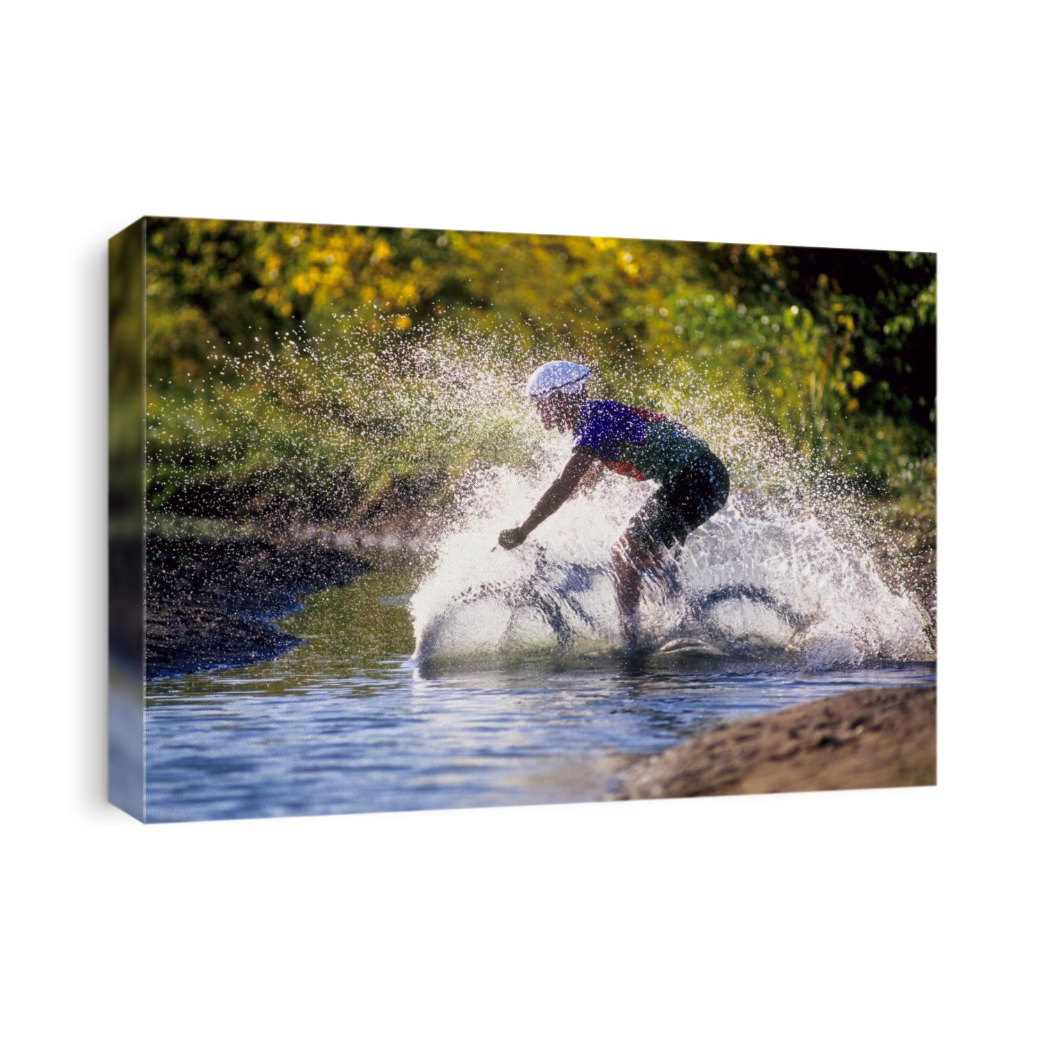 Moutain biker riding through a stream.