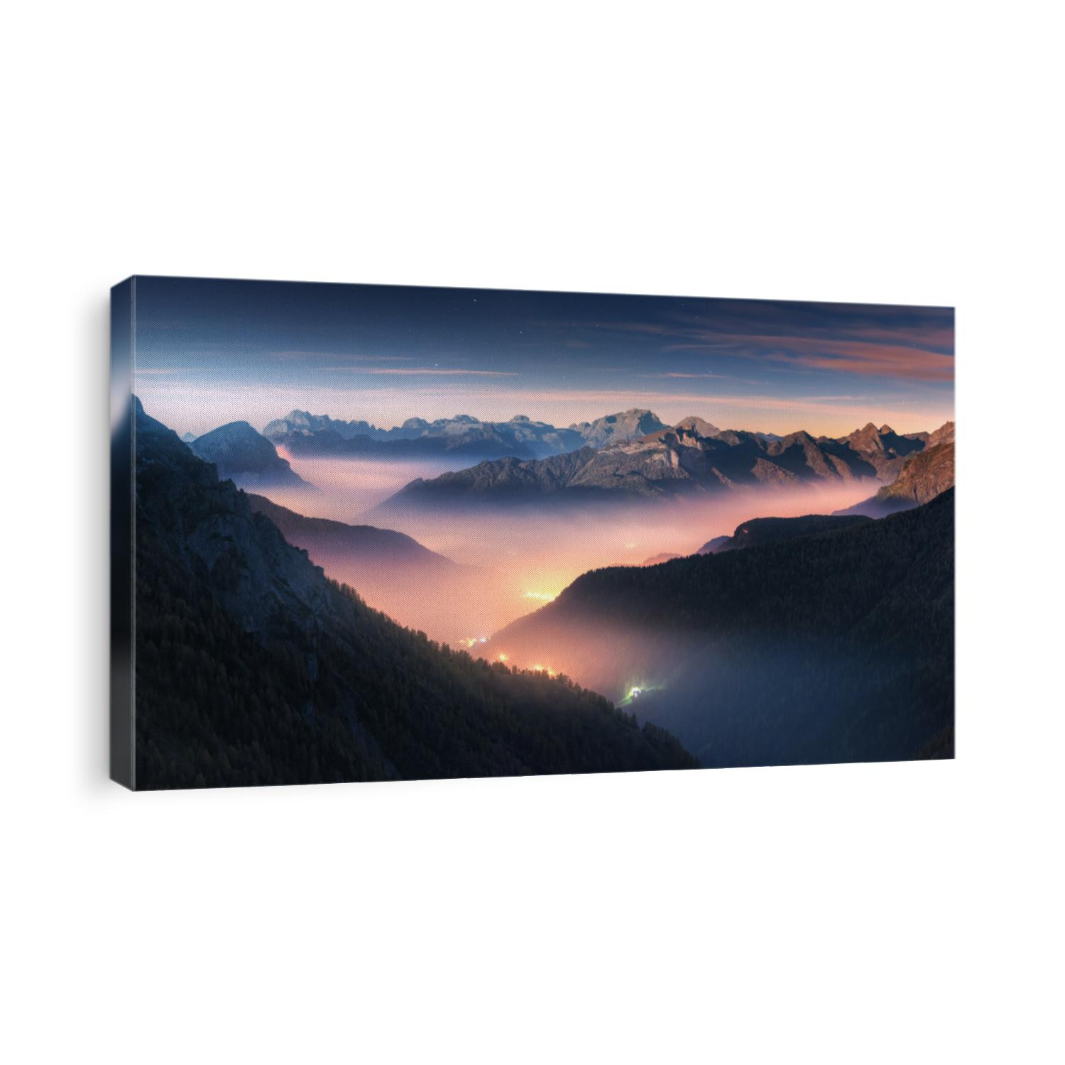 Mountains in fog at beautiful night in autumn in Dolomites, Italy. Landscape with alpine mountain valley, low clouds, forest, colorful sky with stars, city illumination at dusk. Aerial. Passo Giau
