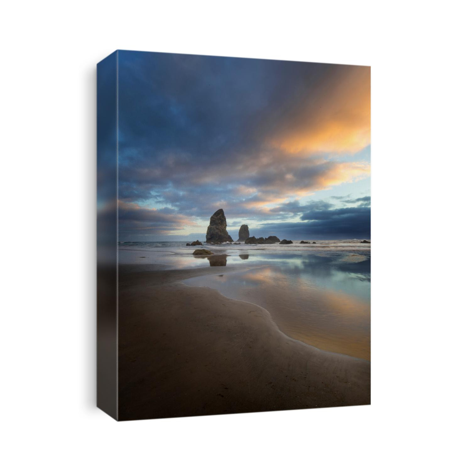 Large rock formations known as sea stacks stand out of the sandy beach on the Pacific Ocean with the sun setting in the distance during low tide.