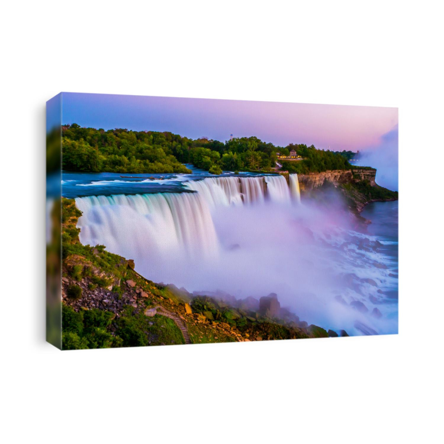 Niagara falls in the summer during beautiful evening, night with clear dark sunset blue sky. Niagara fall water hit with many colorful lights that is beautiful in a way. Sky turning dark and cold.