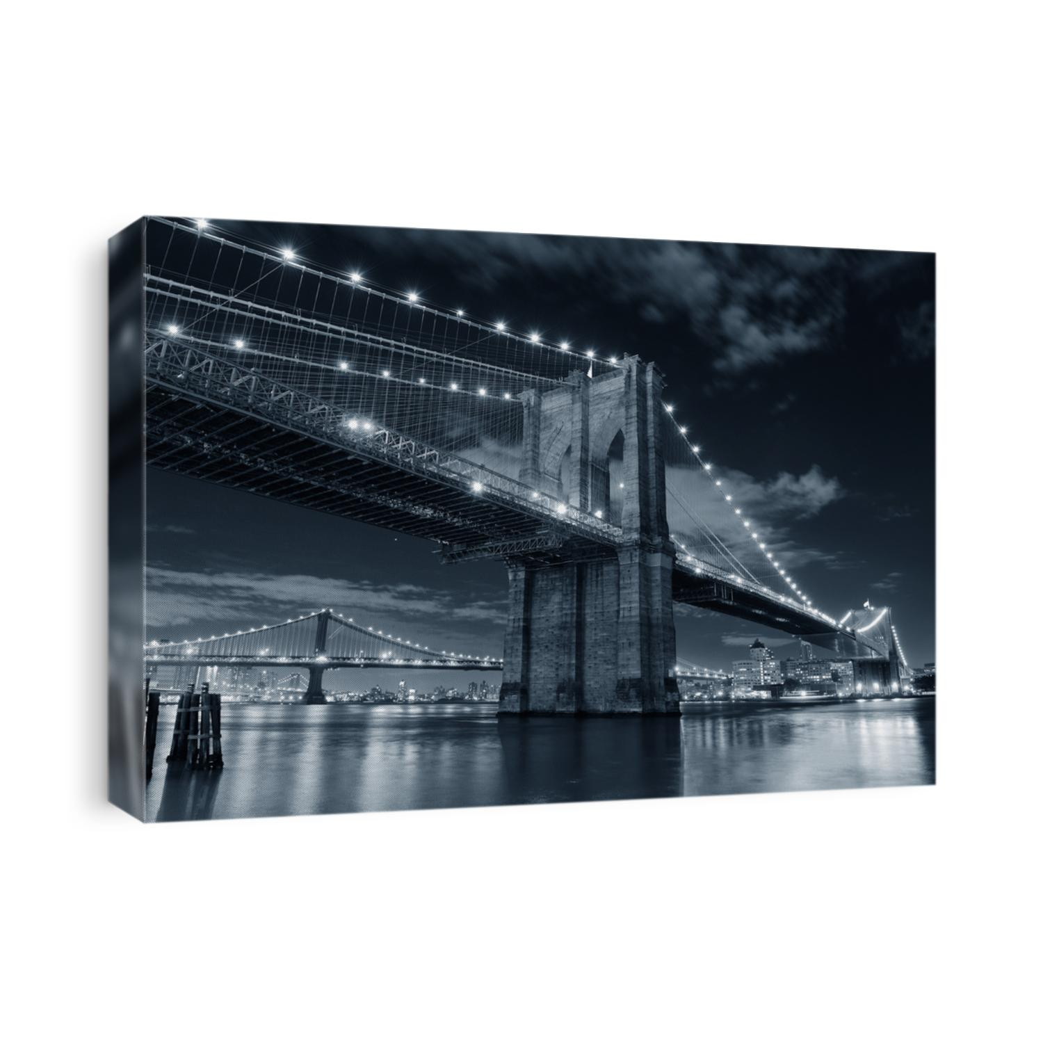 Brooklyn Bridge over East River at night in black and white in New York City Manhattan with lights and reflections.