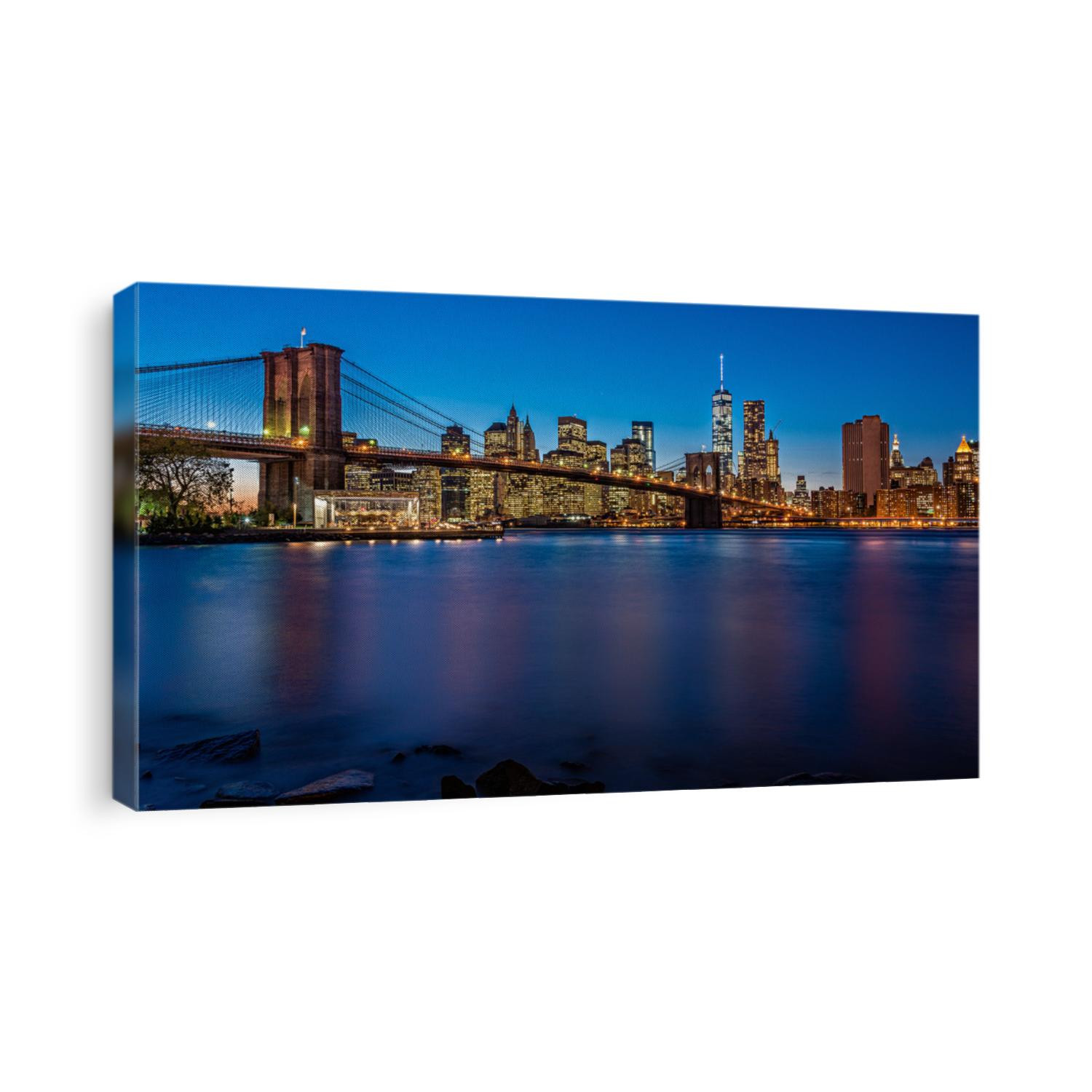 Brooklyn Bridge in the evening with midnight blue sky and smooth water surface shot from Brooklyn side