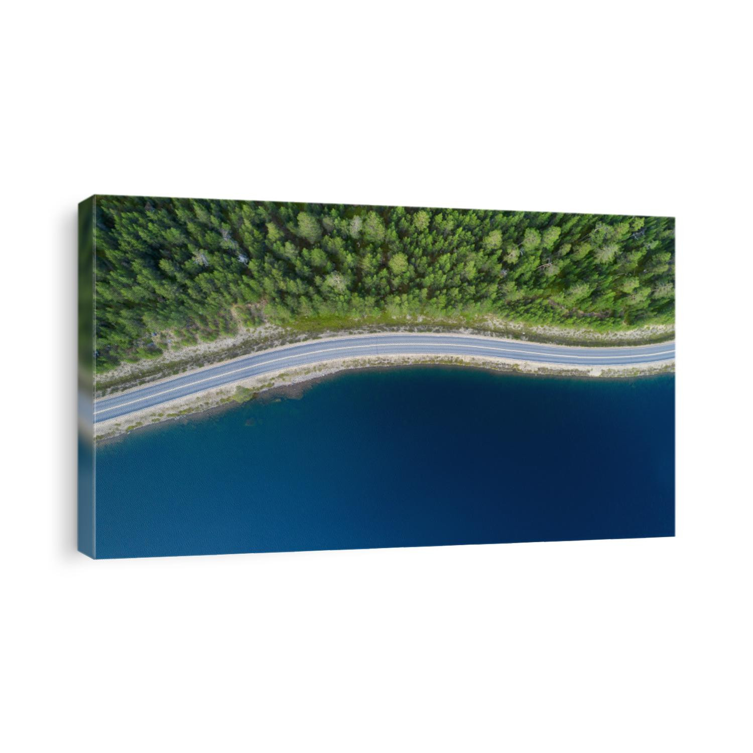 Beautiful aerial view of road between green summer forest and blue lake in Lapland.