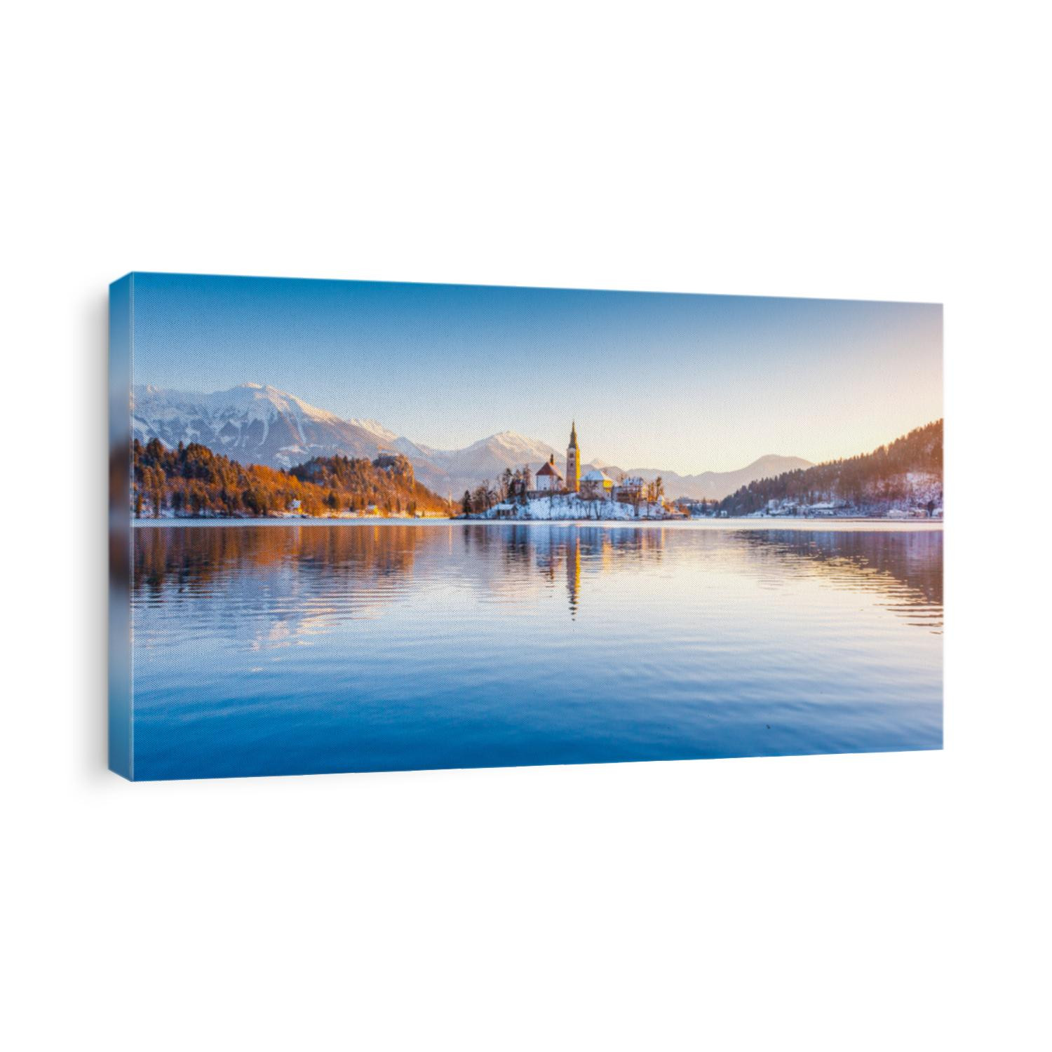 Beautiful view of famous Bled Island (Blejski otok) at scenic Lake Bled with Bled Castle (Blejski grad) and Julian Alps in the background in golden morning light at sunrise in winter, Slovenia